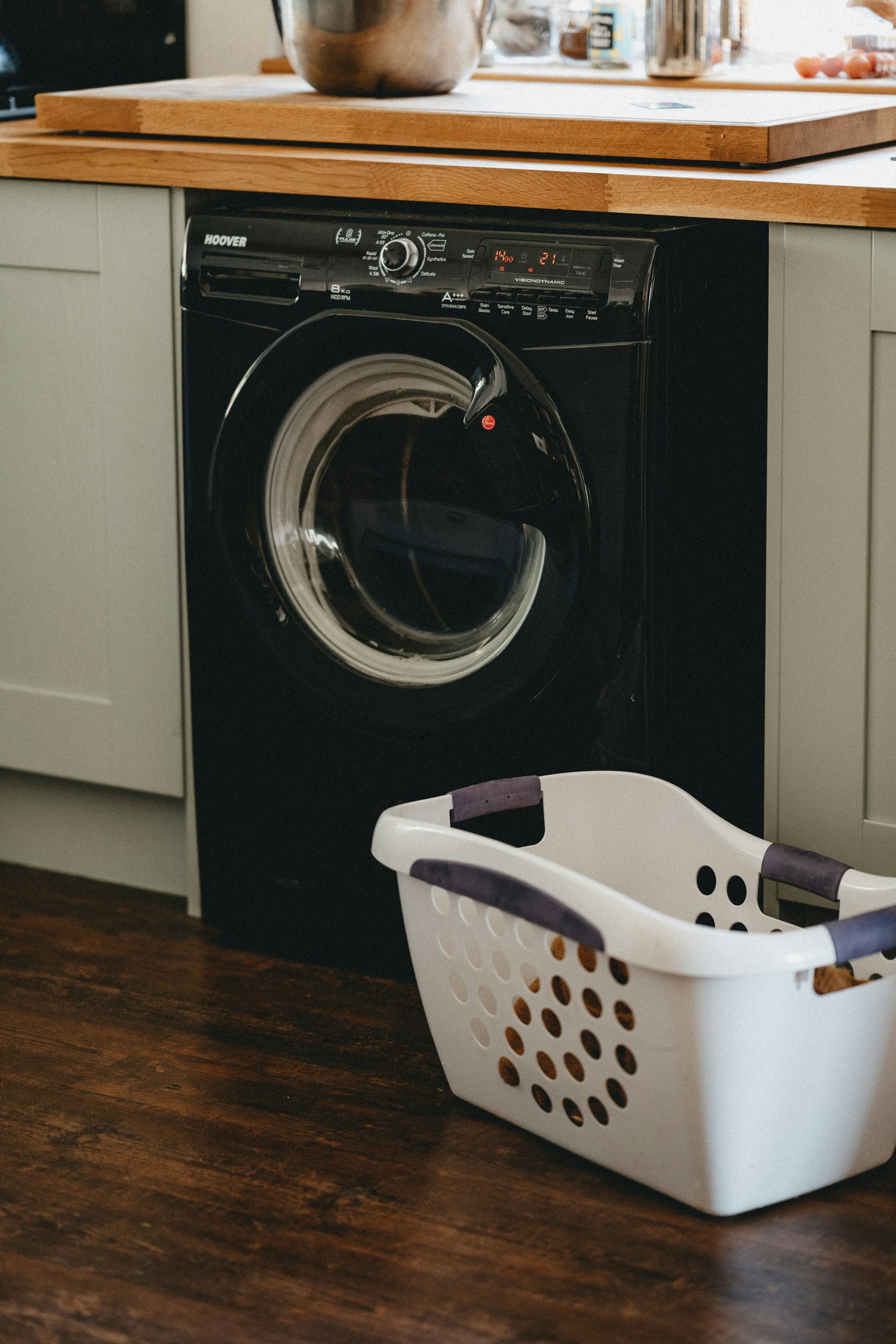 white laundry basket sitting on dark hardwood floors next to black washing machine