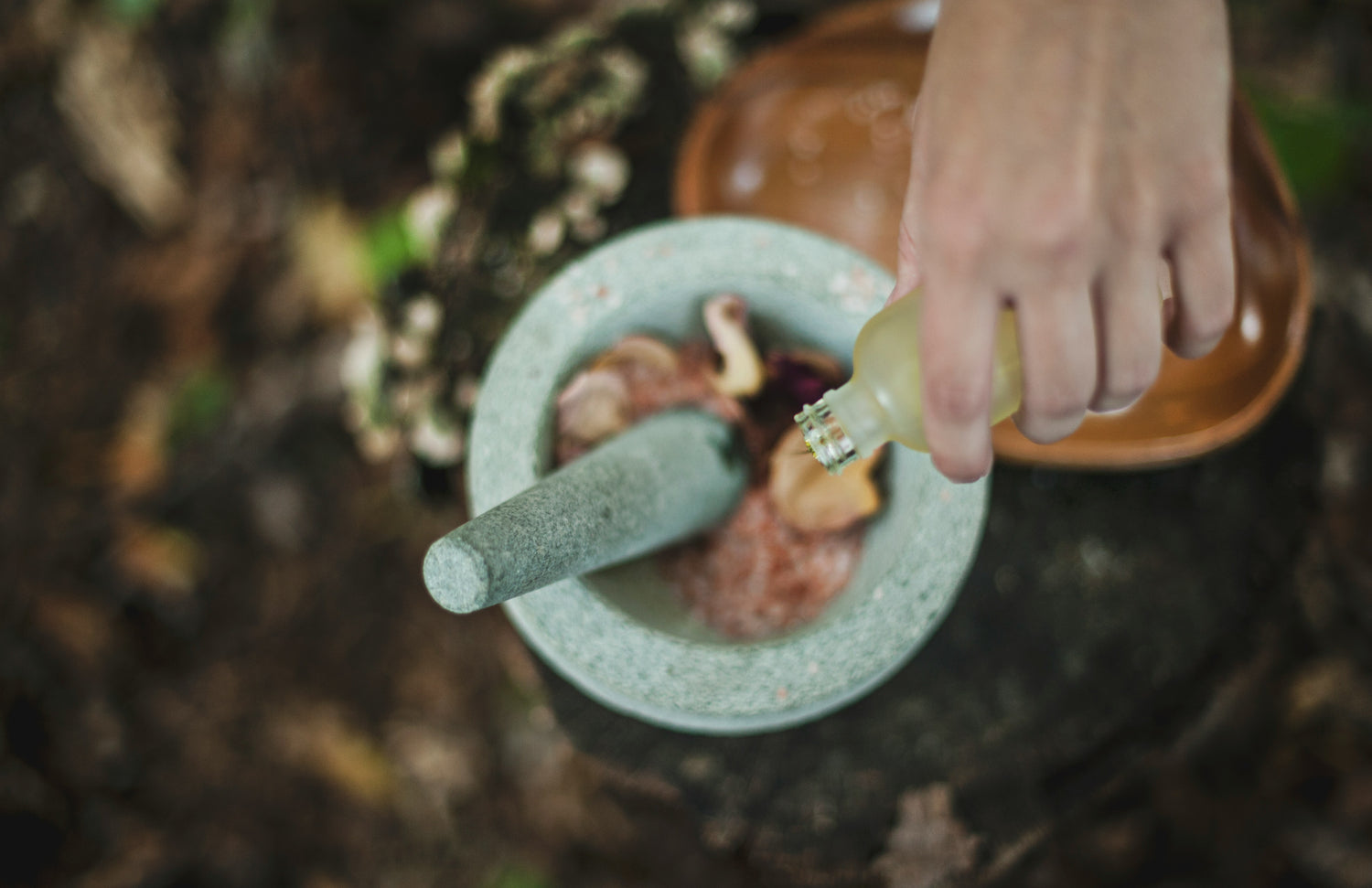 hand pouring liquid into mortar & pestle