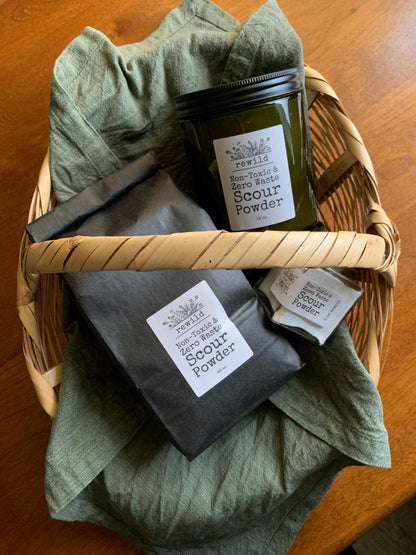 3 different sizes of scour powder (3 oz sample jar, 18 oz jar, 48 oz refill bag) in a woven basket