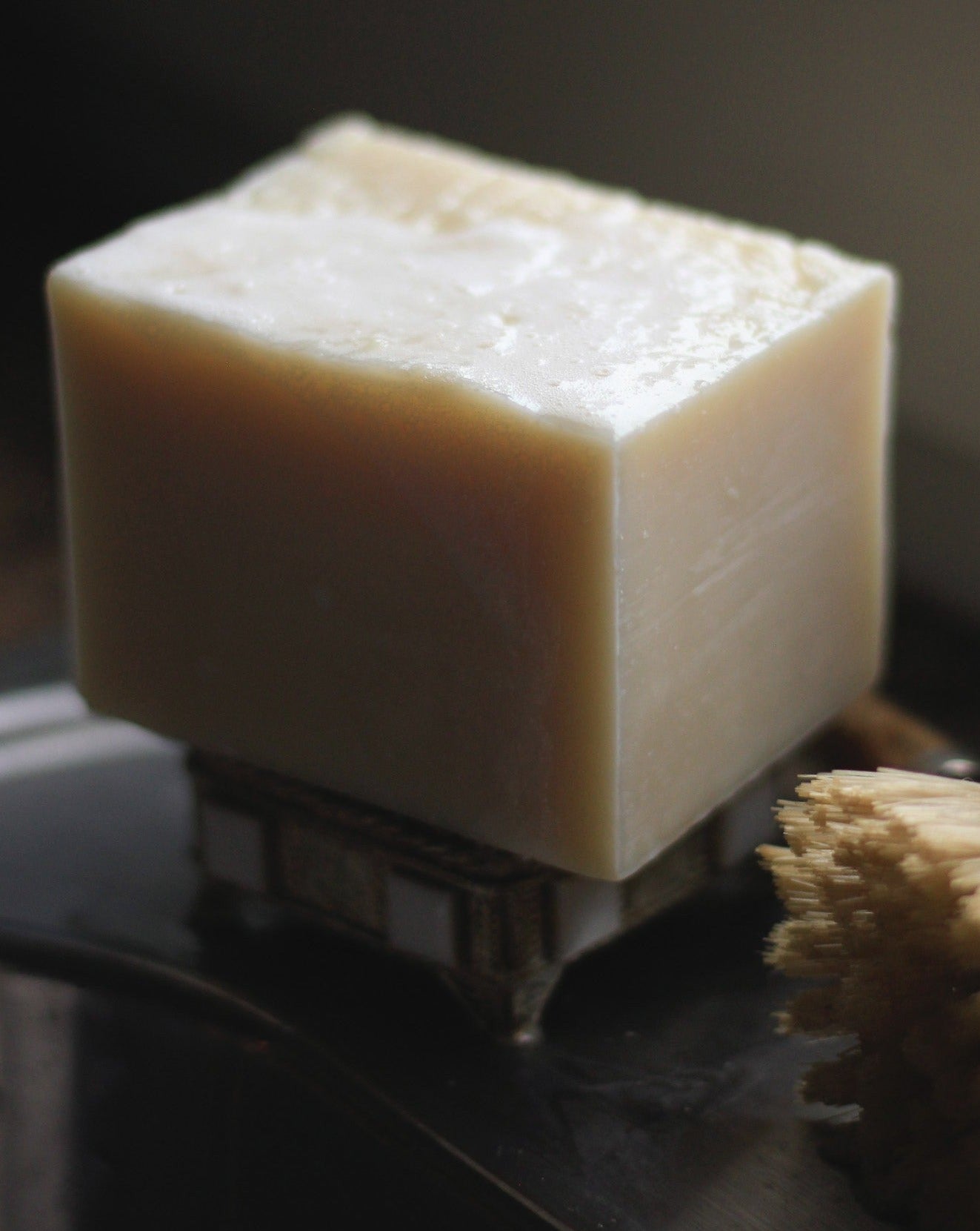 closeup of solid dish soap next to dish scrubber brush