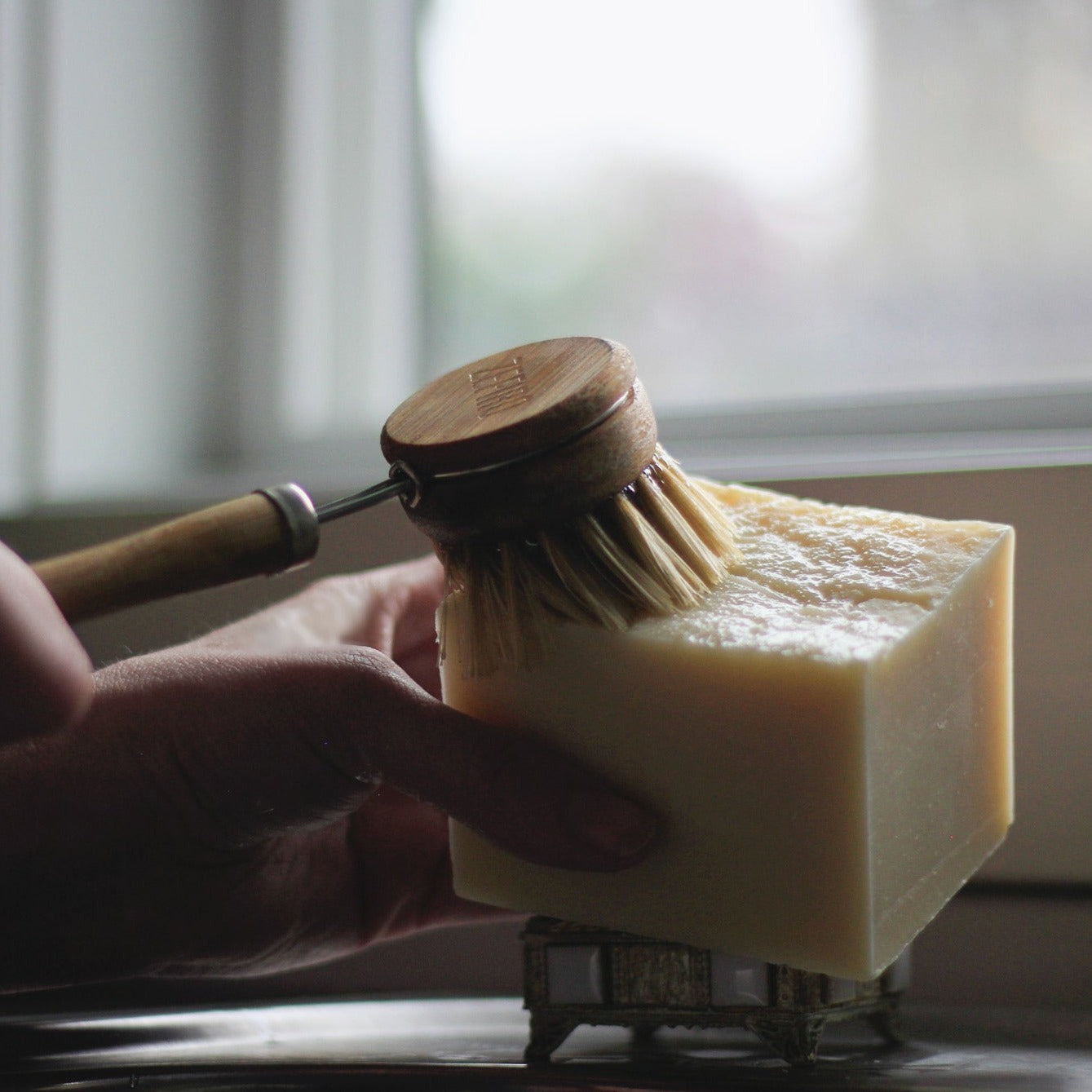 hand scrubbing dish brush on solid dish soap