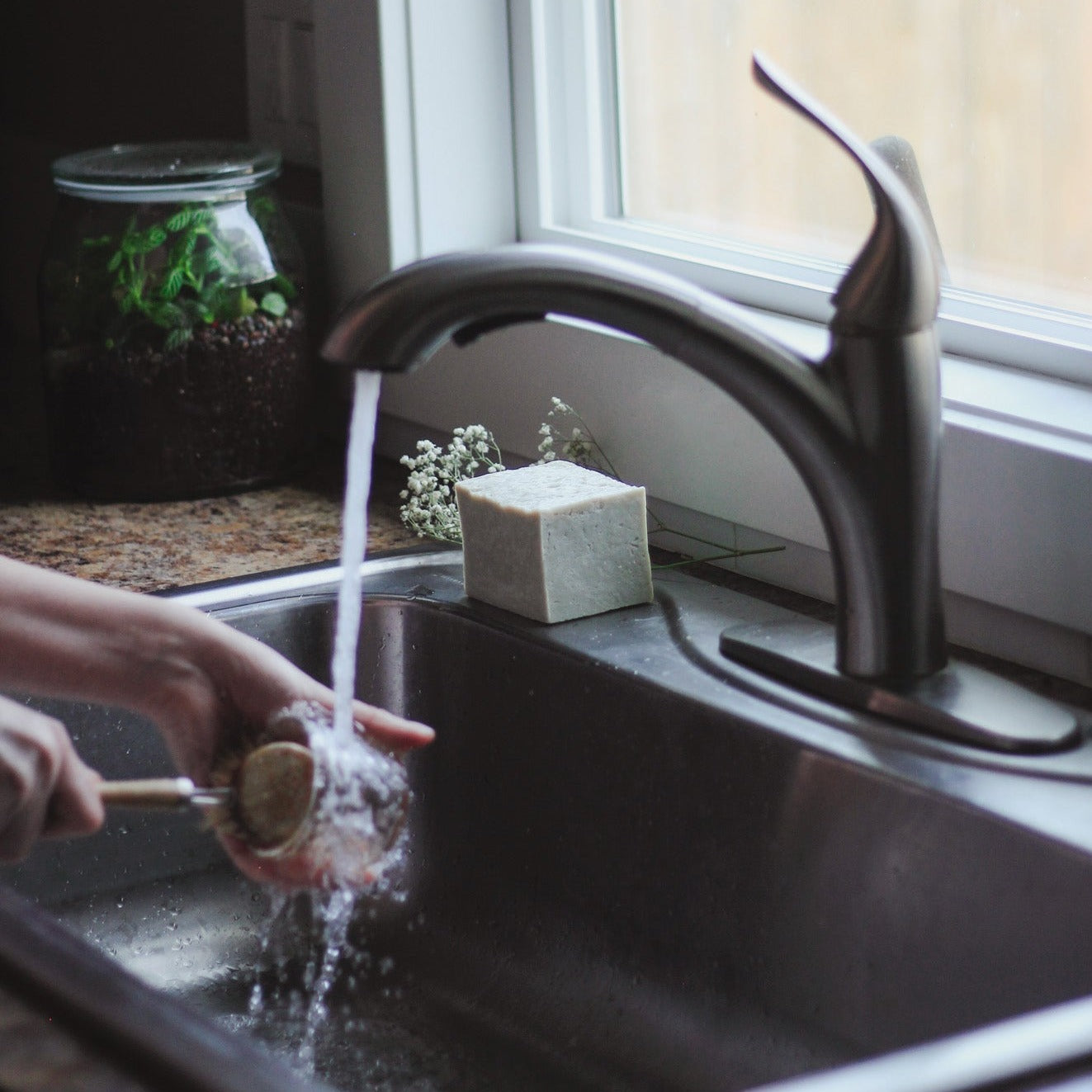 hand washing dishes with block of solid dish soap on kitchen sink