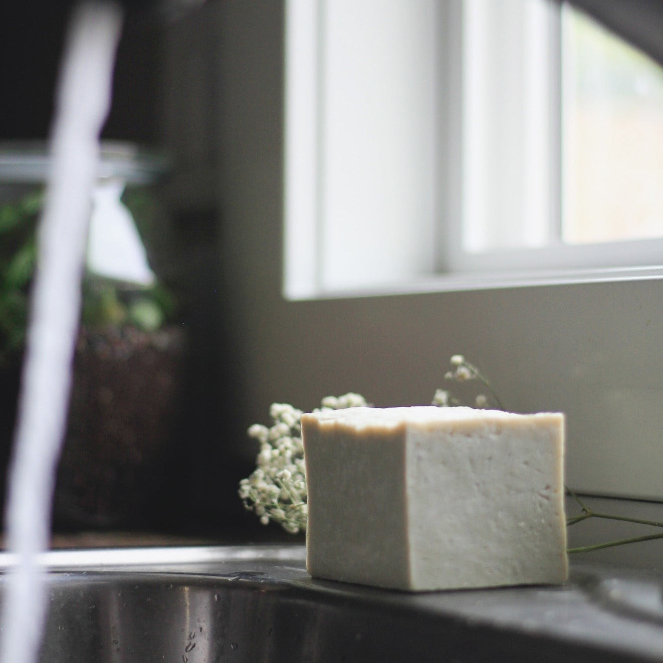 solid dish soap sitting on kitchen sink with faucet running