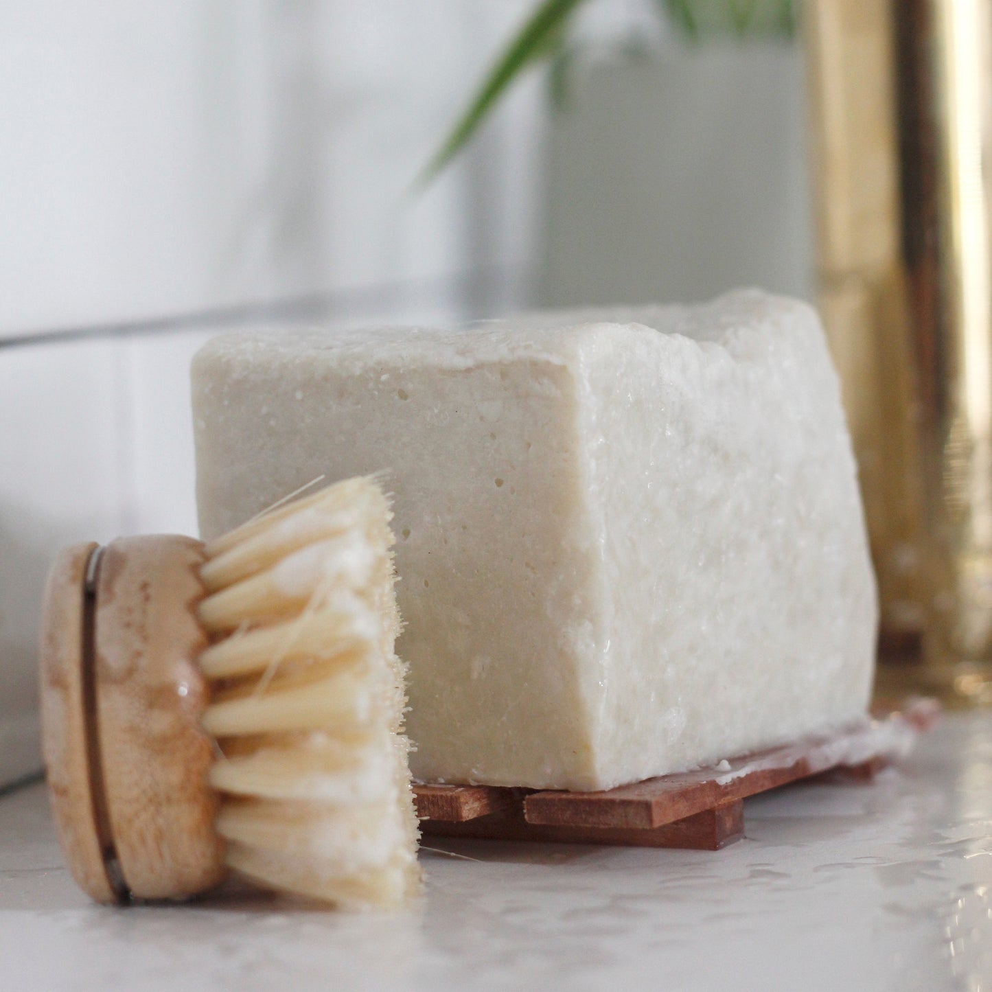 a large block of solid dish soap sitting on a wood soap dish next to a dish scrubber