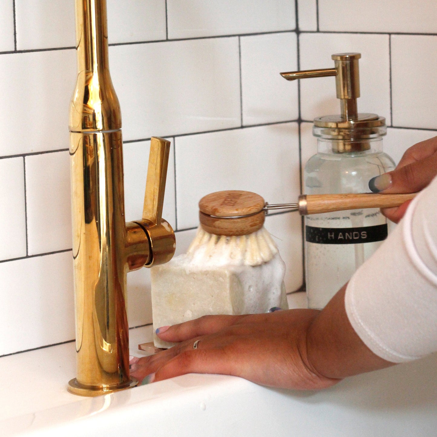 hand rubbing a dish scrub brush on a block of solid dish soap at kitchen sink