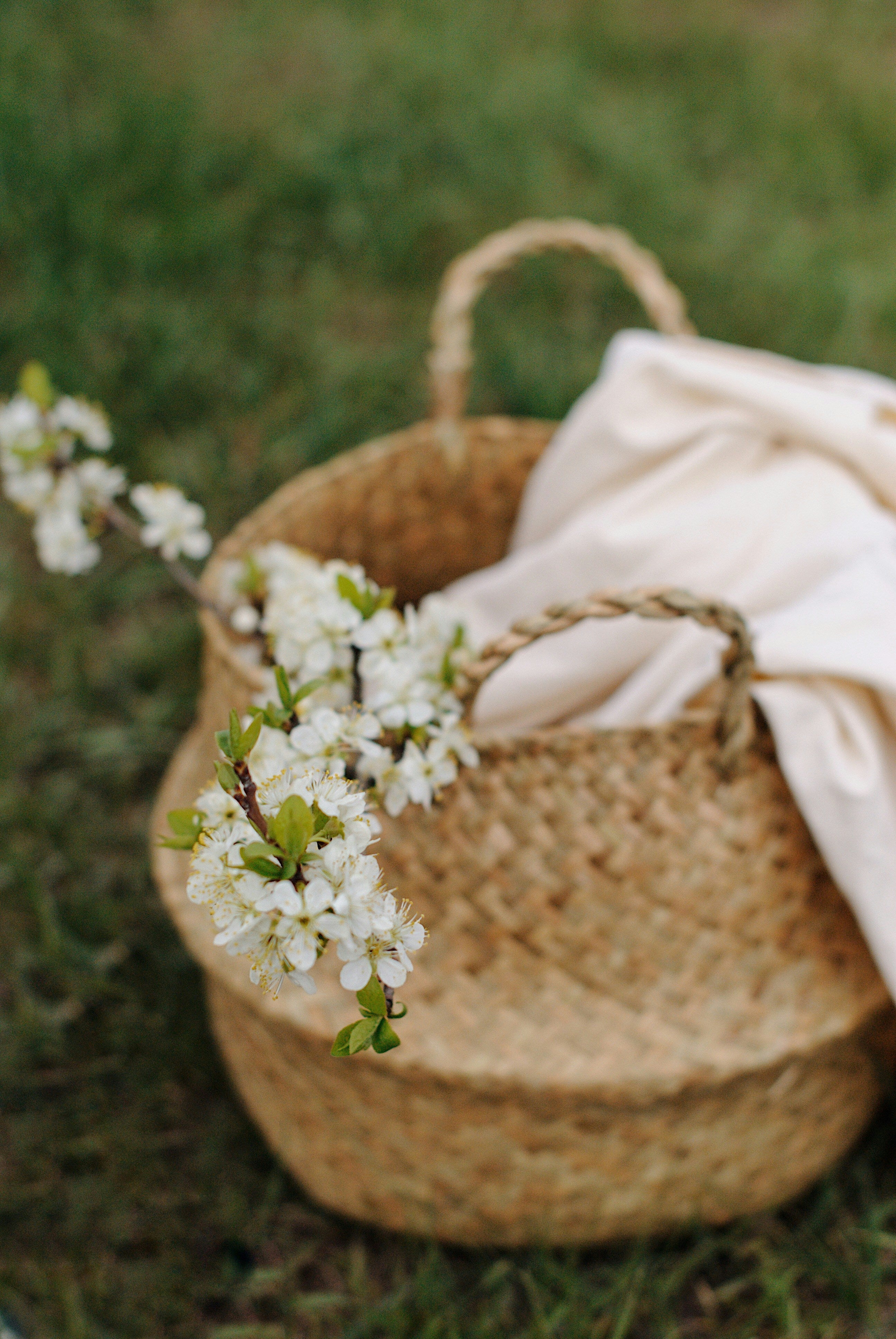 a white sheet and white flowers in a woven laundry basket outside