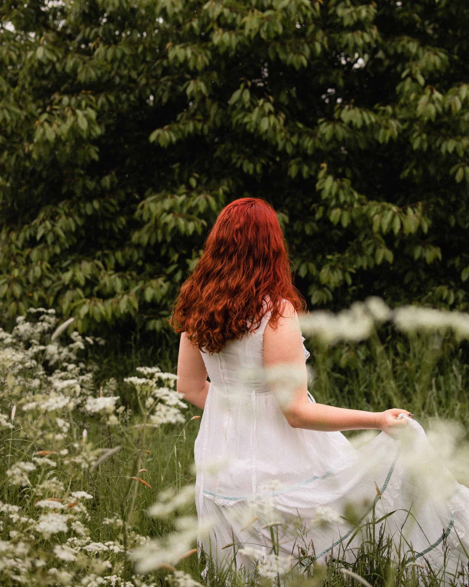 red-haired woman in white dress in a field of wildflowers
