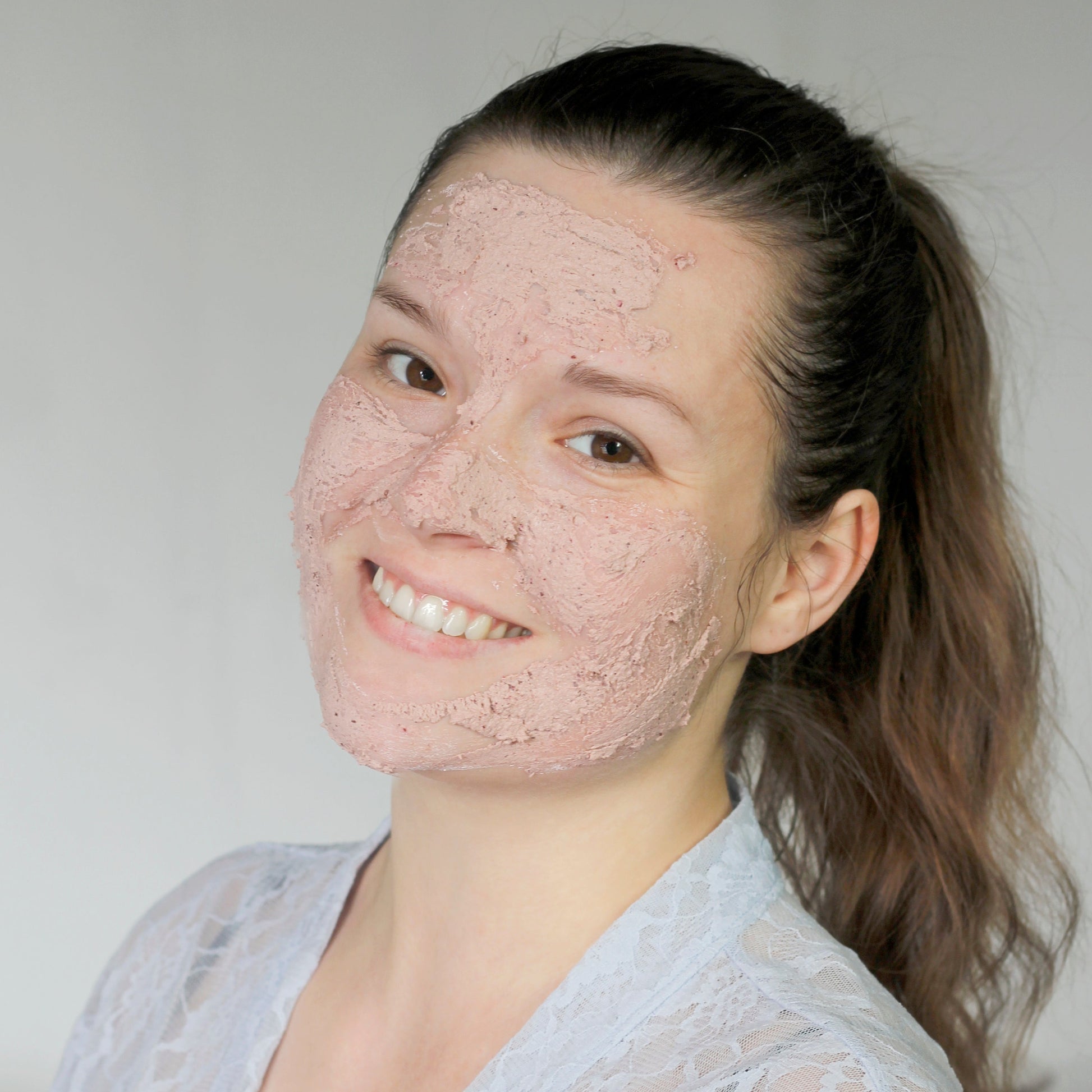 a smiling woman with face mask powder on her face