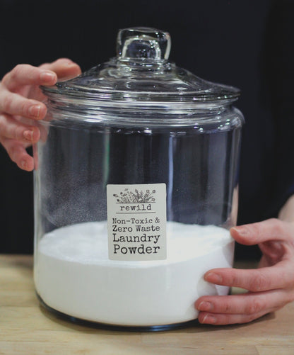 hands holding a large glass jar of laundry powder