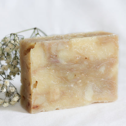 bar of soap on white background with small white dried flowers next to it